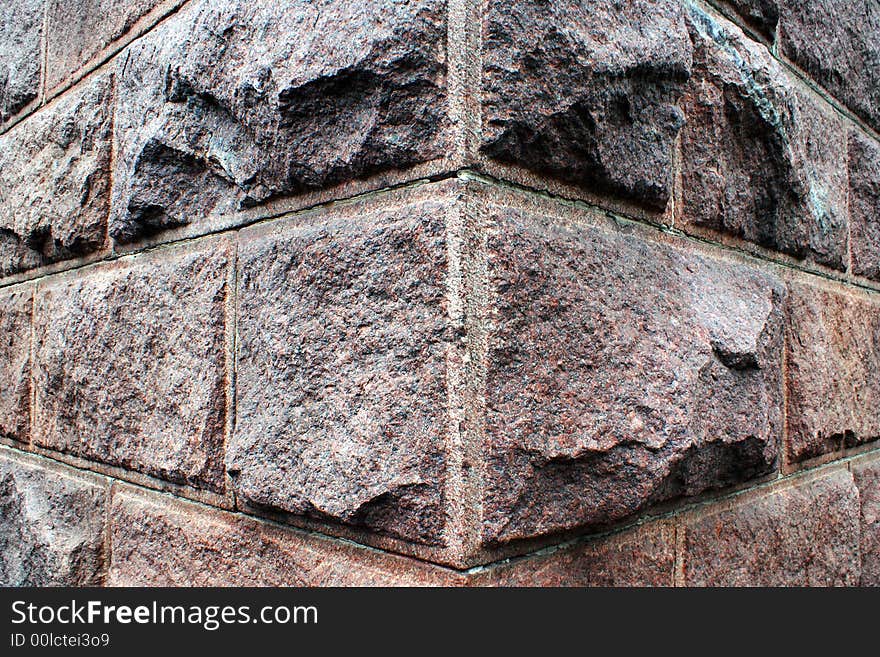 A decorative background, a corner of a wall of a building from rough stone blocks. A decorative background, a corner of a wall of a building from rough stone blocks.