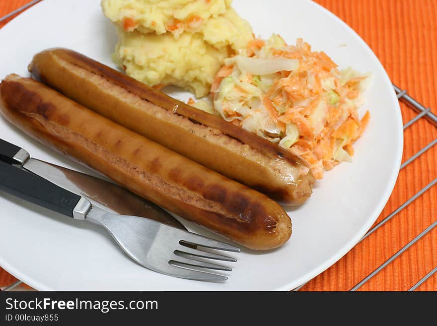 Pan grilled jumbo frankfurters with side serving of mash and coleslaw