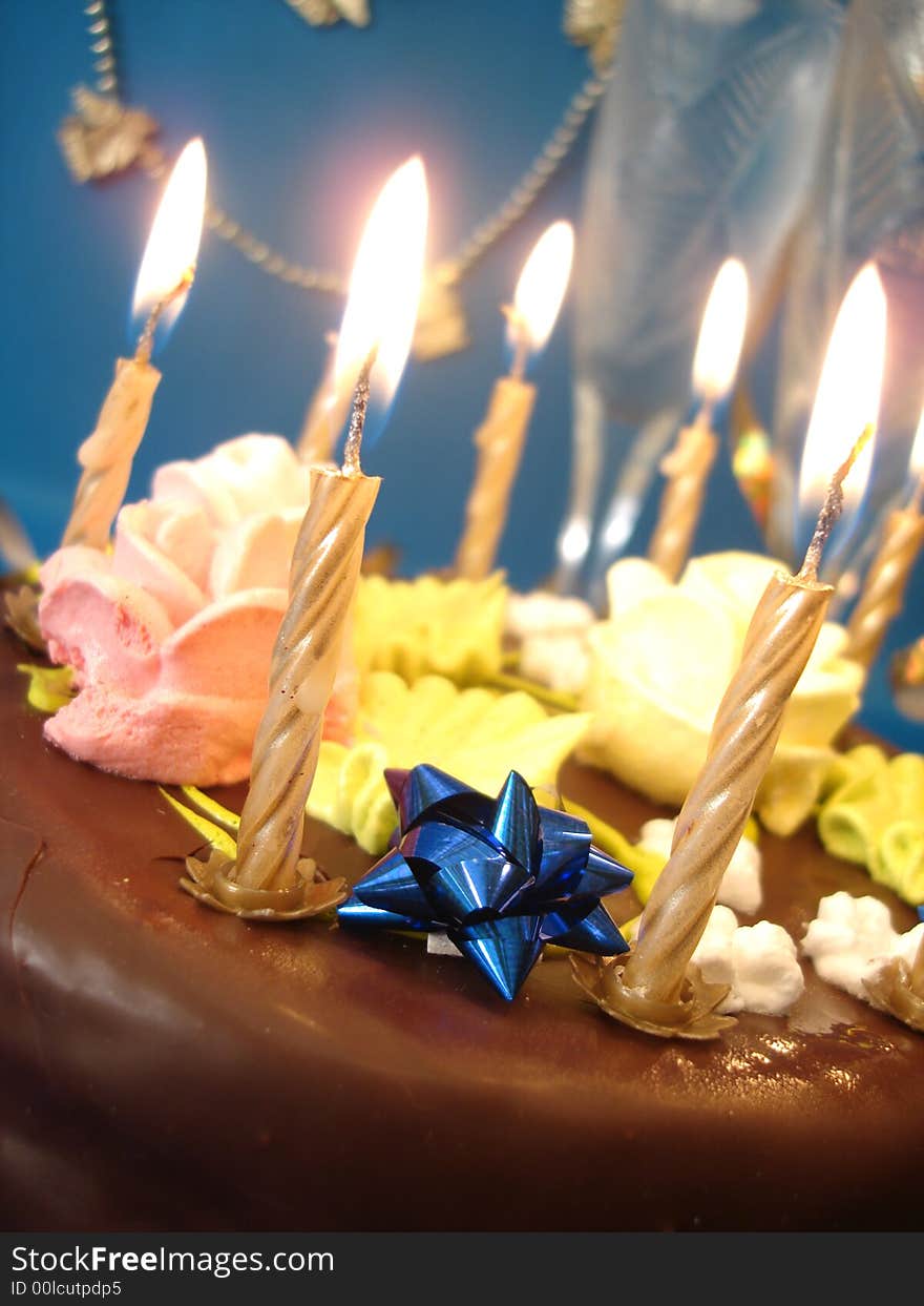 Cake and candles, two glasses with champagne on blue