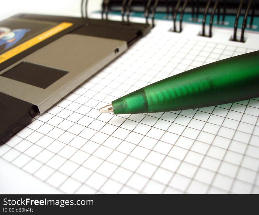 Close-up of pen and diskette on notebook