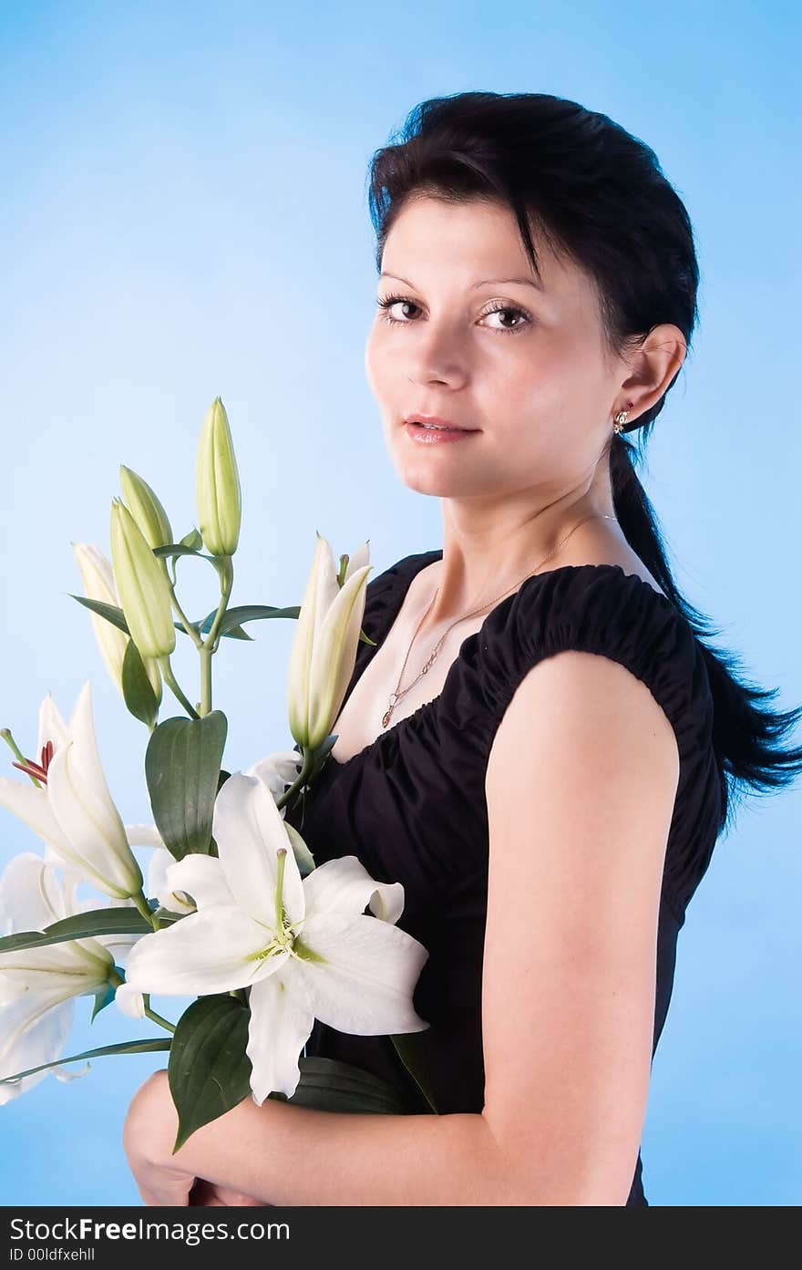 The attractive woman with a bouquet of lilies isolated on a dark blue background.