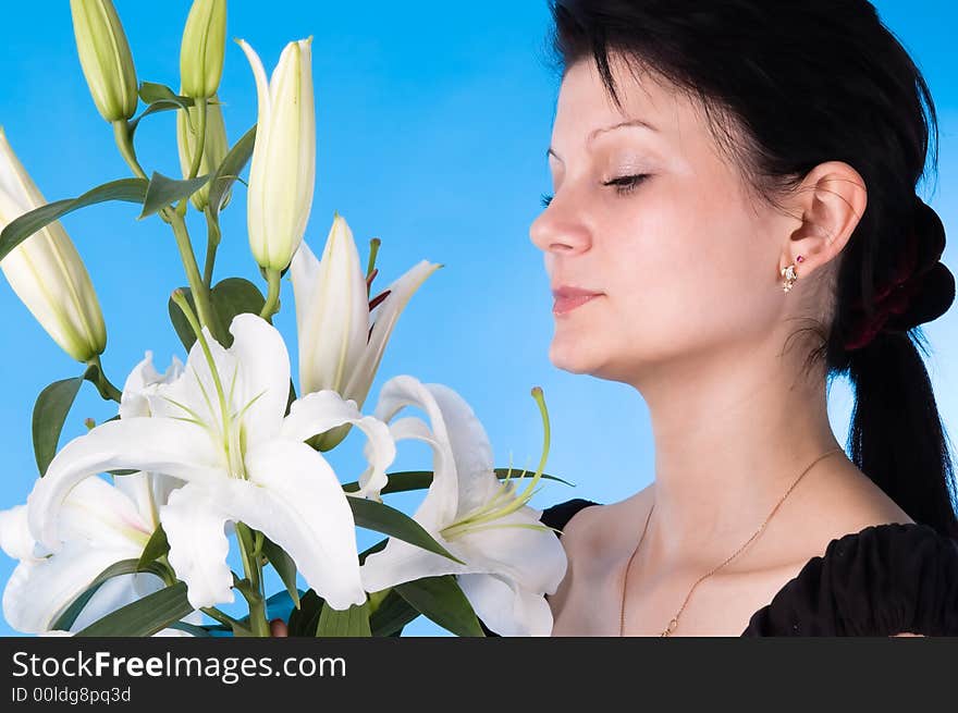 The attractive woman with a bouquet of lilies isolated on a dark blue background.