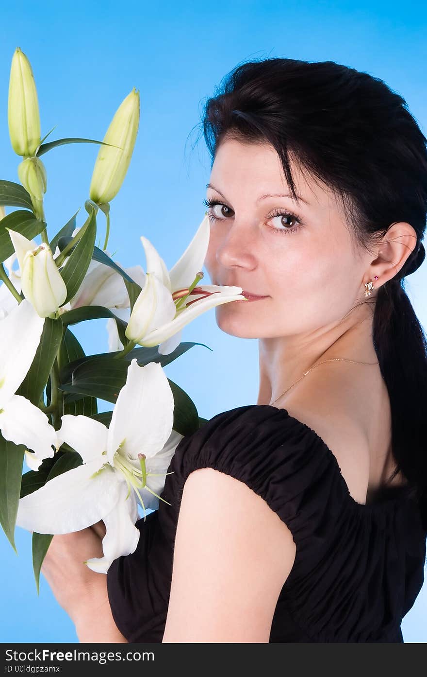 The attractive woman with a bouquet of lilies isolated on a dark blue background.