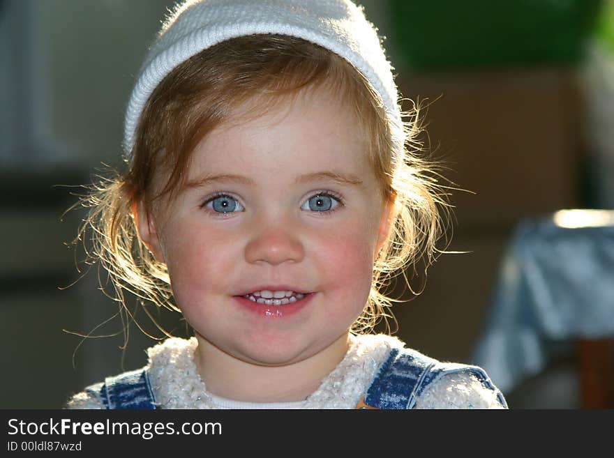 Smiley little girl in white hat over defocused background