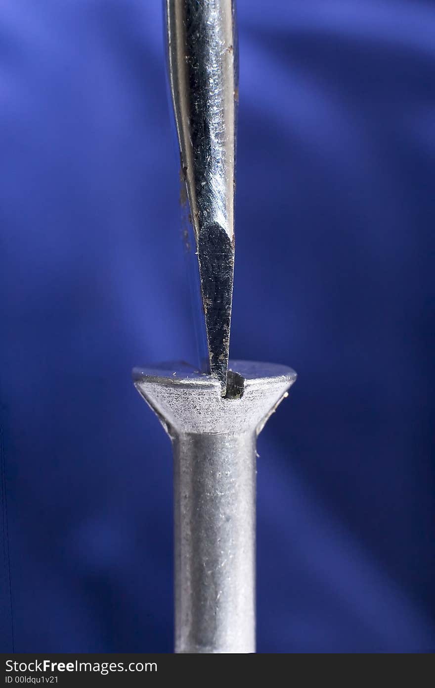 A close up of a screwdriver tightening a screw. A close up of a screwdriver tightening a screw