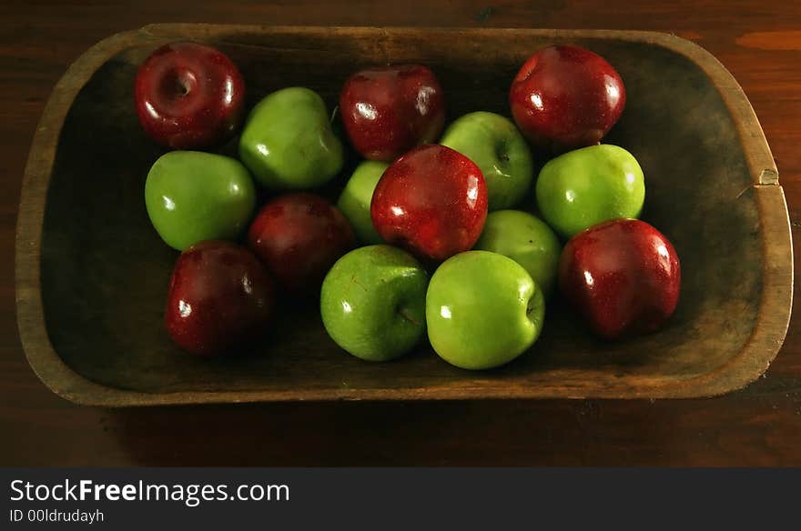 Red and green waxed apples in an antique wooden bowl. Red and green waxed apples in an antique wooden bowl.