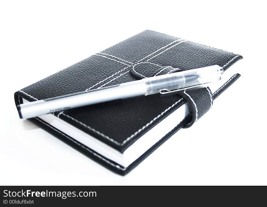 Black leather cased notebook, on white bacground with pen for writing. Black leather cased notebook, on white bacground with pen for writing.