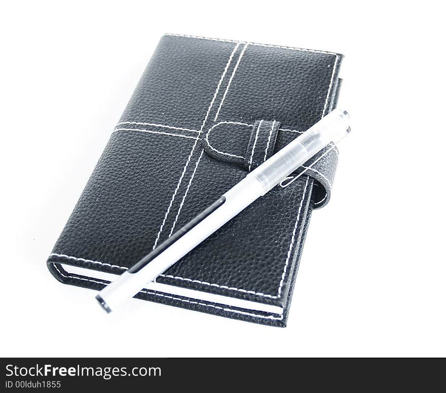 Black leather cased notebook, on white bacground with pen for writing. Black leather cased notebook, on white bacground with pen for writing.