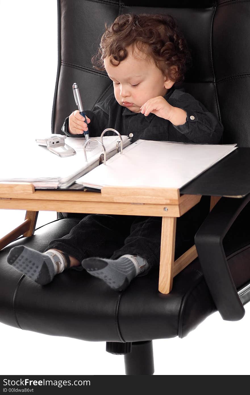 Little boss signs documents at his desk in an office chair. Little boss signs documents at his desk in an office chair.