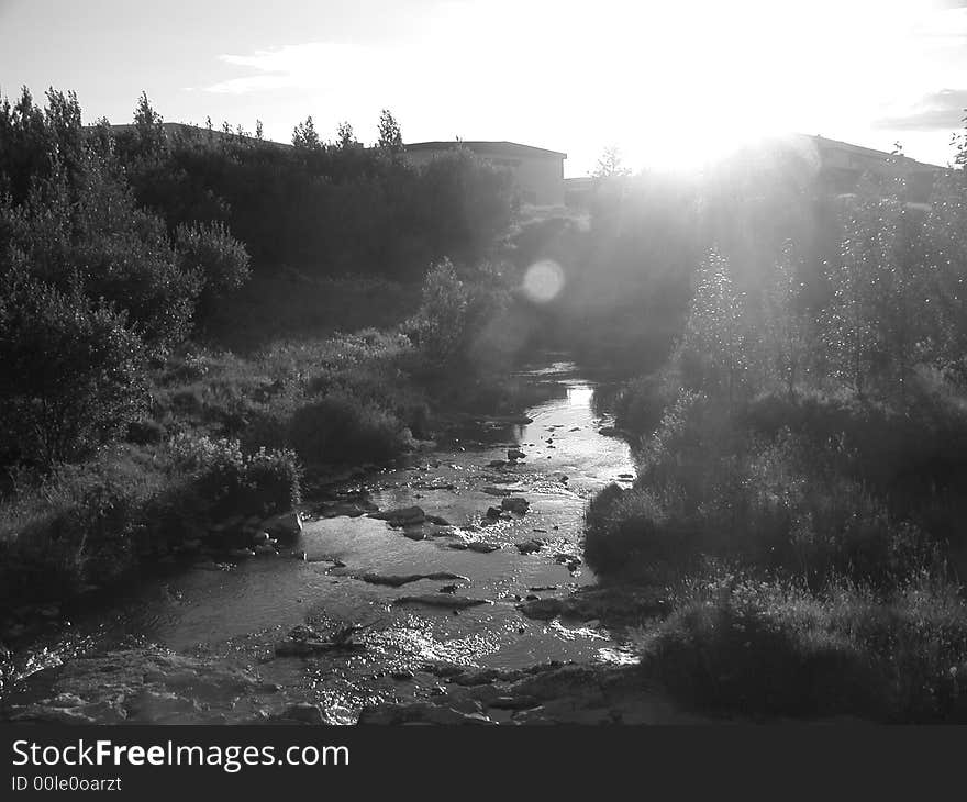 The sun is nearly setting over an idyllic stream and nearby stable. The sun is nearly setting over an idyllic stream and nearby stable.