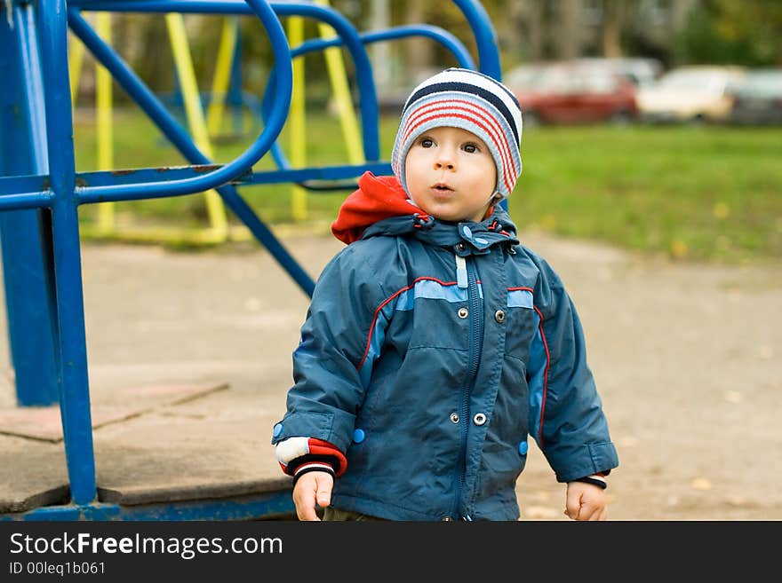 The child the boy on a children's playground at a swing. The child the boy on a children's playground at a swing