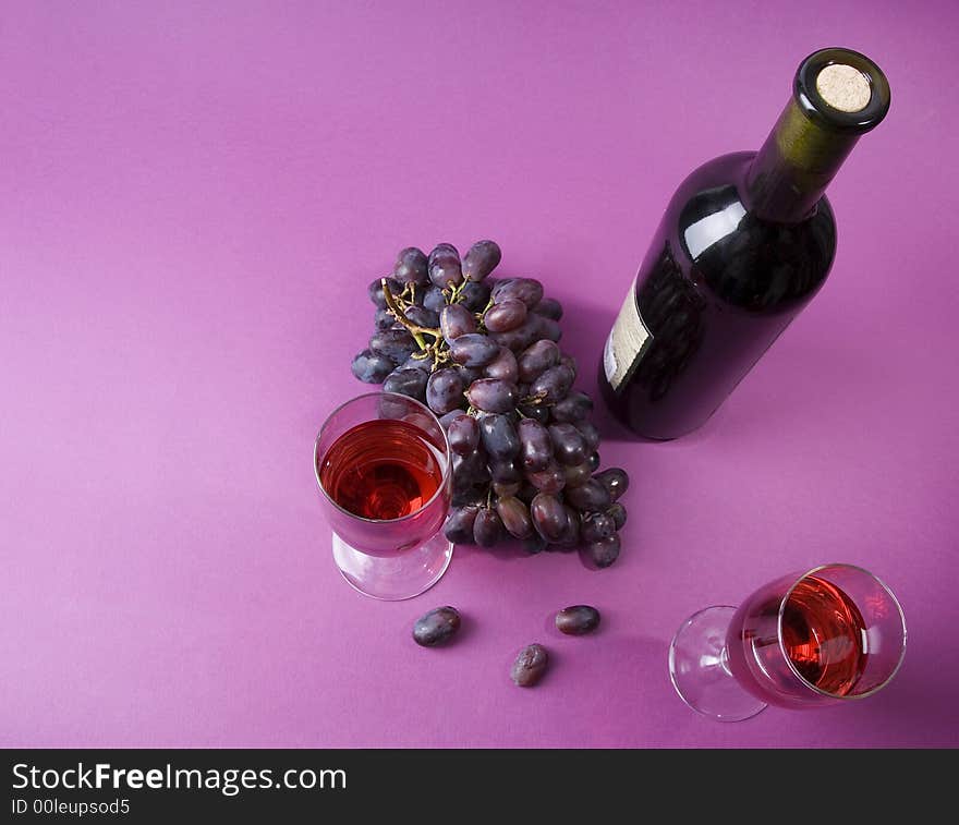 2 glasses of wine, bottle of wine and grape on the violet background