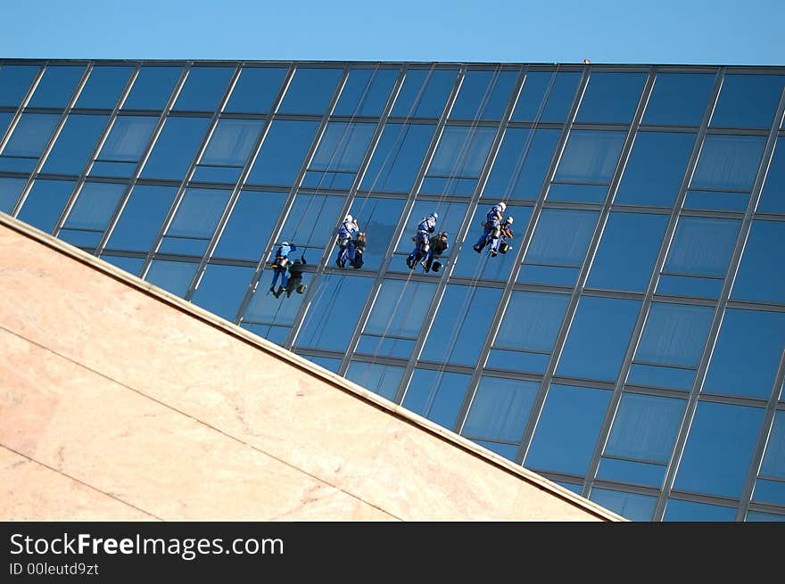 Four cleaners washing the glass building. Four cleaners washing the glass building