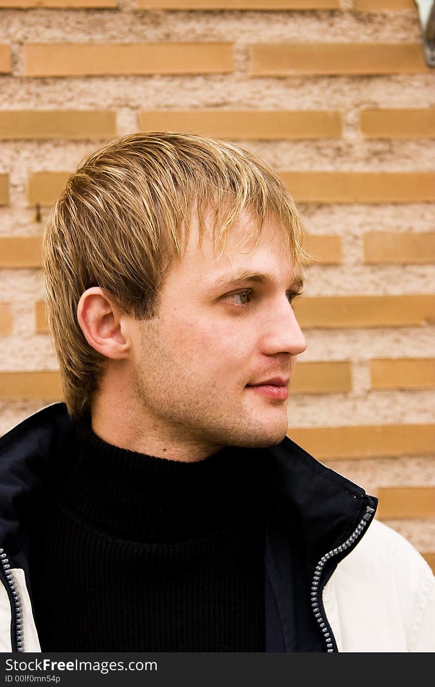 Young man portrait, outdoors,  brick wall background