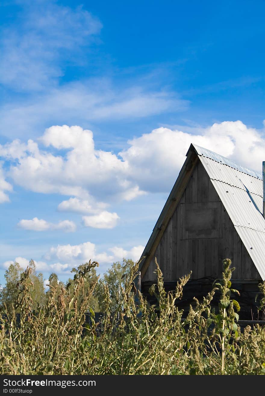 Photo of lonely village house with blue sky and clouds on the background. Photo of lonely village house with blue sky and clouds on the background