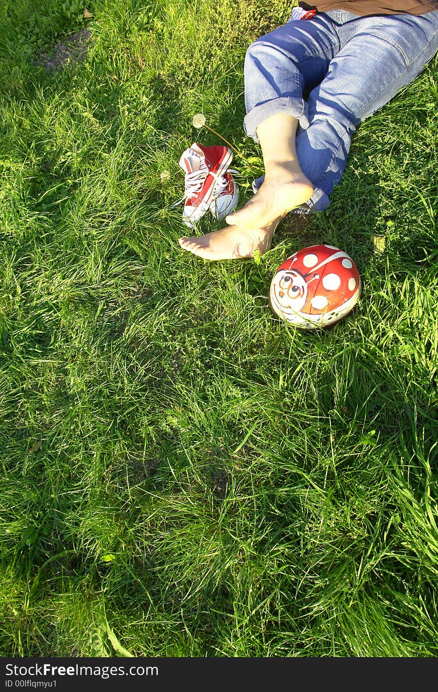 Bare feet, and red snickers resting on grass. Bare feet, and red snickers resting on grass