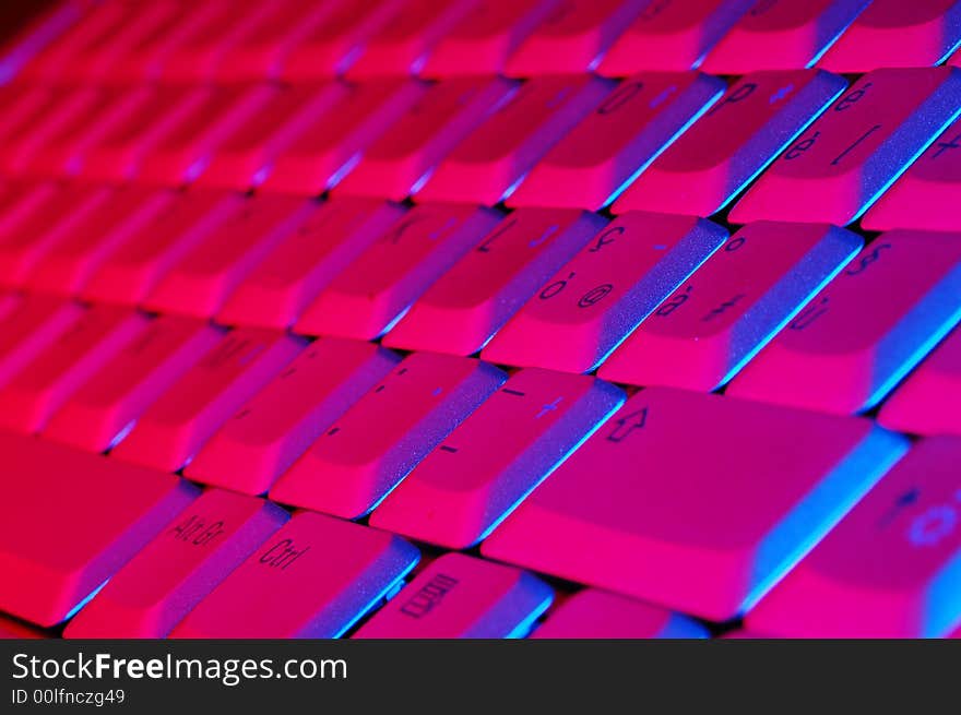 Close-up photo of the keyboard of an open notebook; blue red tone. Close-up photo of the keyboard of an open notebook; blue red tone