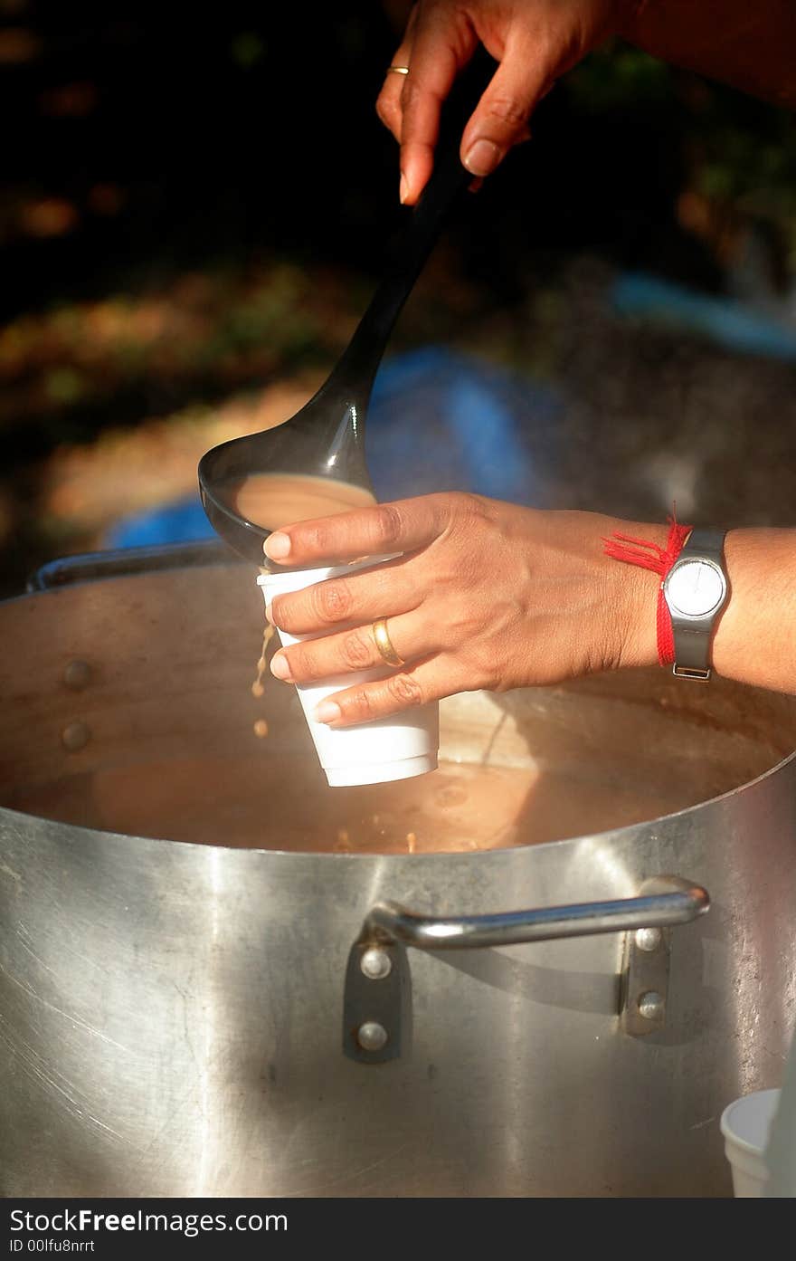 Person serving traditional Sri Lankan tea at an outdoor party. Person serving traditional Sri Lankan tea at an outdoor party