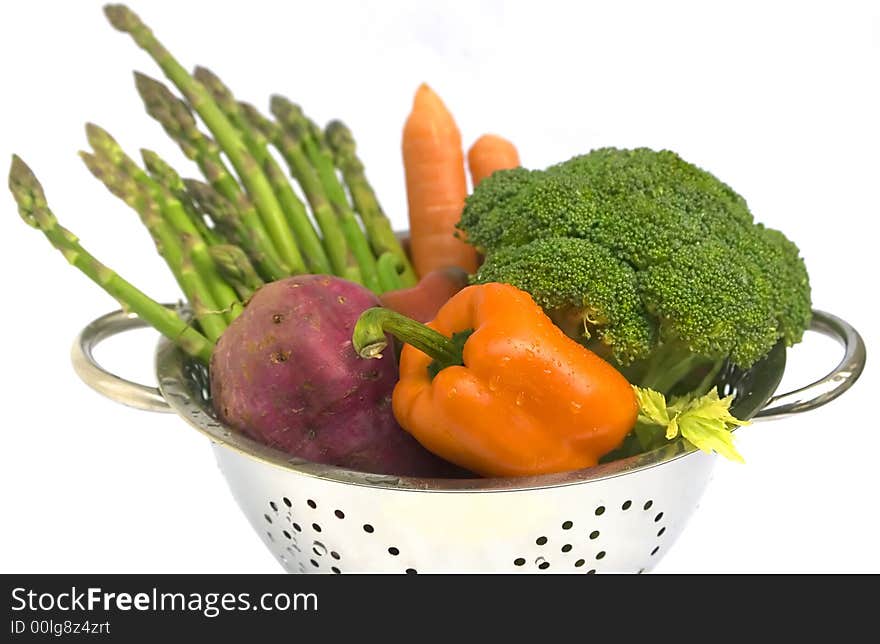 Fresh vegetables - asparagus, carrots, broccoli, batat and capsicum in steel colander with water drops. On white background, isolated. Shallow DoF. Fresh vegetables - asparagus, carrots, broccoli, batat and capsicum in steel colander with water drops. On white background, isolated. Shallow DoF.