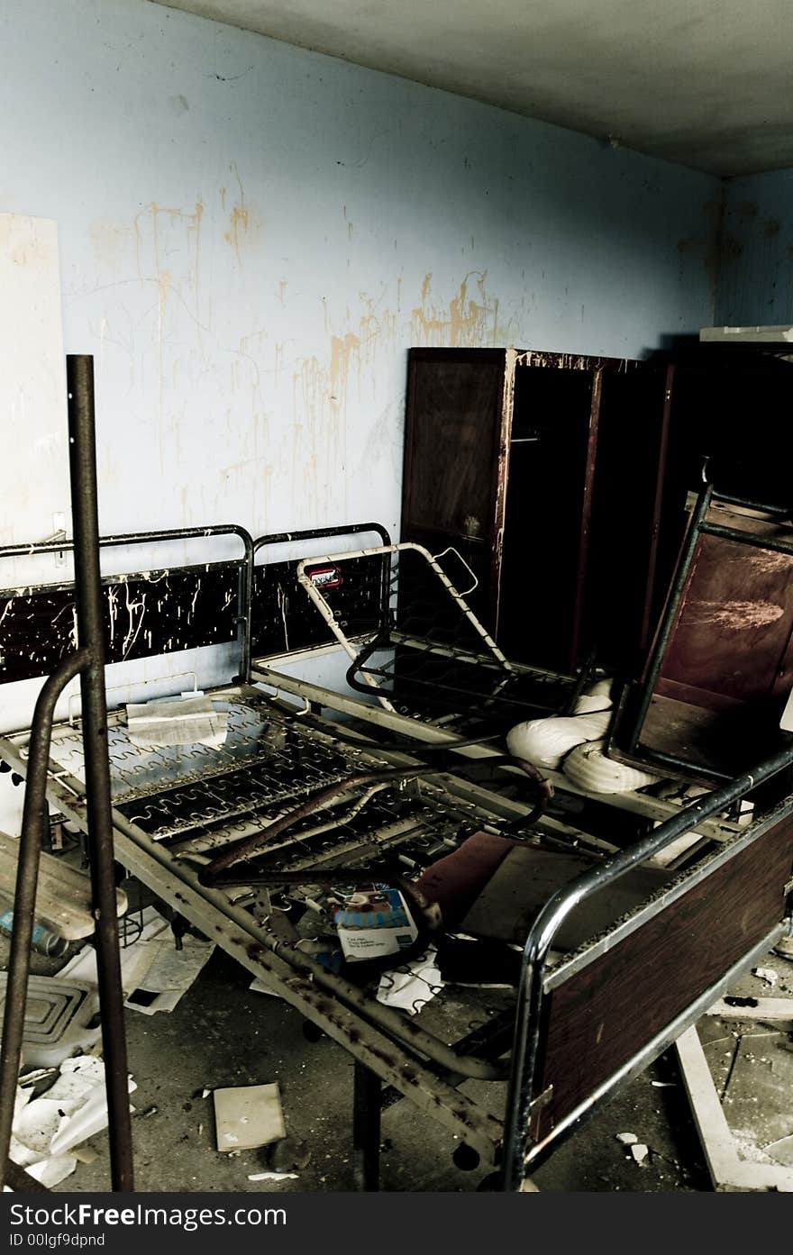 An empty bed frame left behind in a vandalised building