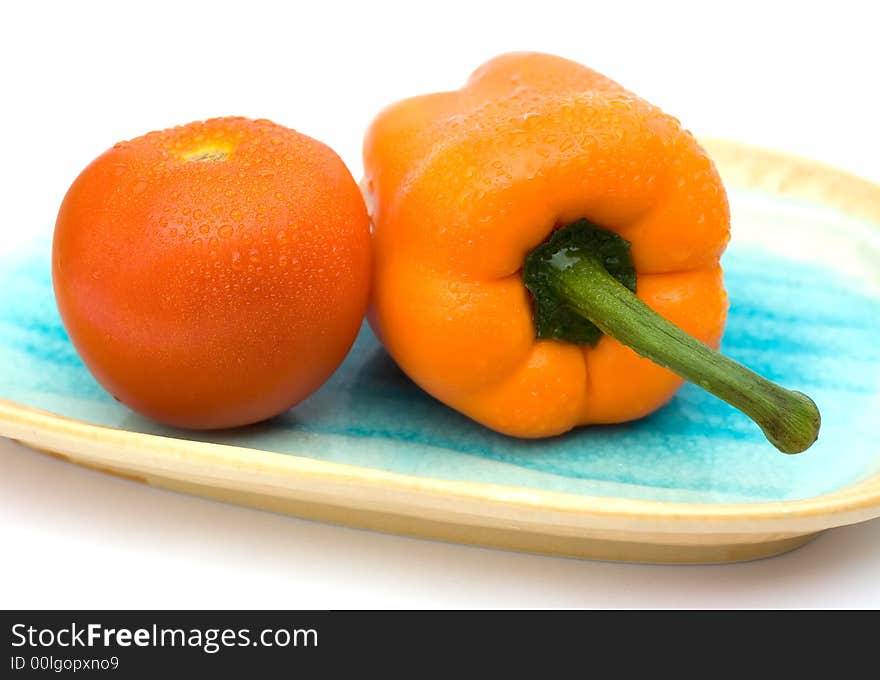 Tomato and capsicum on a shelling plate. Tomato and capsicum on a shelling plate