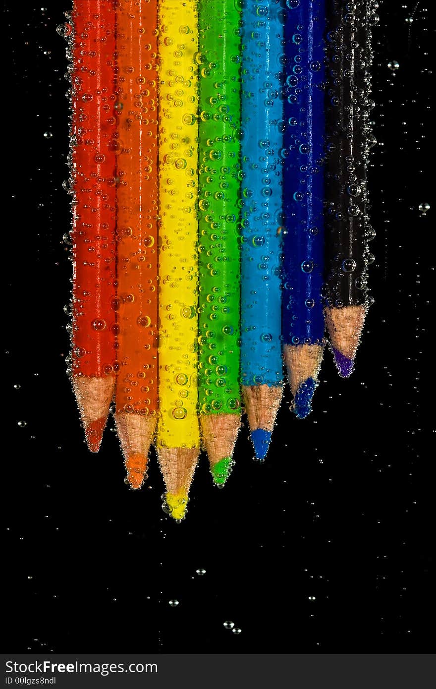 Brightly colored pencils in clear, bubbly liquid. Black background. Brightly colored pencils in clear, bubbly liquid. Black background.