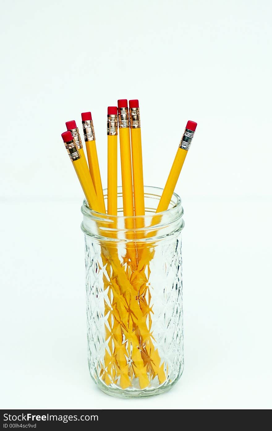 Eight yellow pencils in patterned glass jelly jar, isolated against white. Eight yellow pencils in patterned glass jelly jar, isolated against white