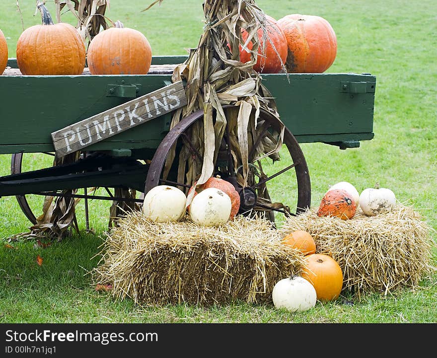 Autumn seasonal display of pumpkins, gourds and straw bales by an old wagon. Autumn seasonal display of pumpkins, gourds and straw bales by an old wagon