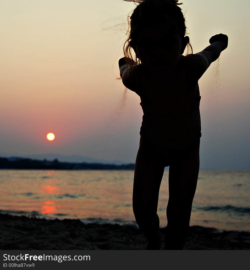 Young kid girl throwing sand on sunset beach. Young kid girl throwing sand on sunset beach