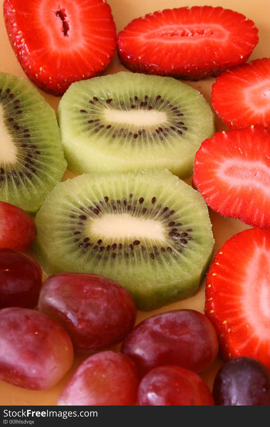 Colourful sliced and whole fruits on a yellow plate. Colourful sliced and whole fruits on a yellow plate