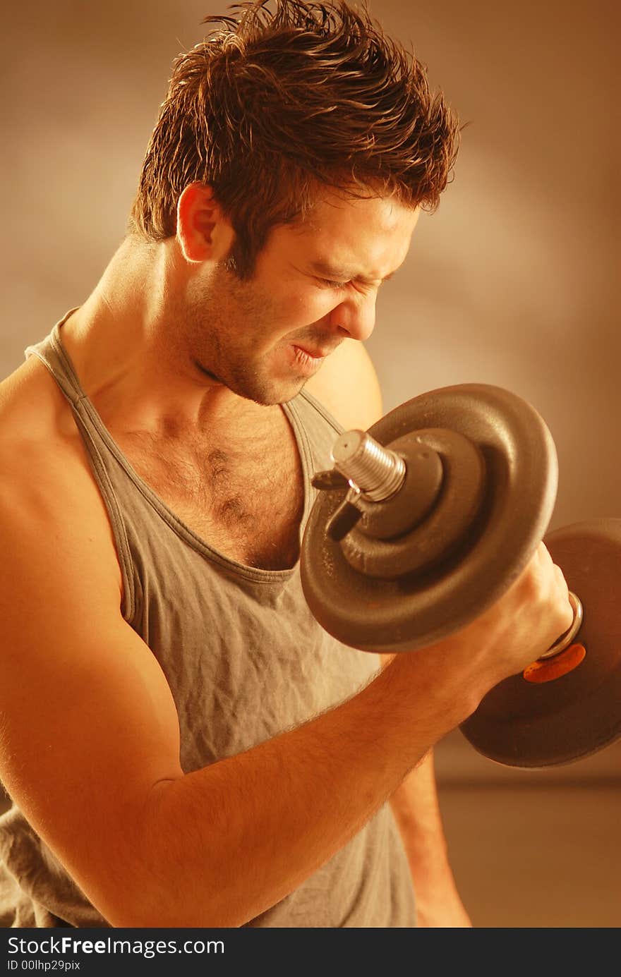 A strong man exercising with a dumb-bell. A strong man exercising with a dumb-bell