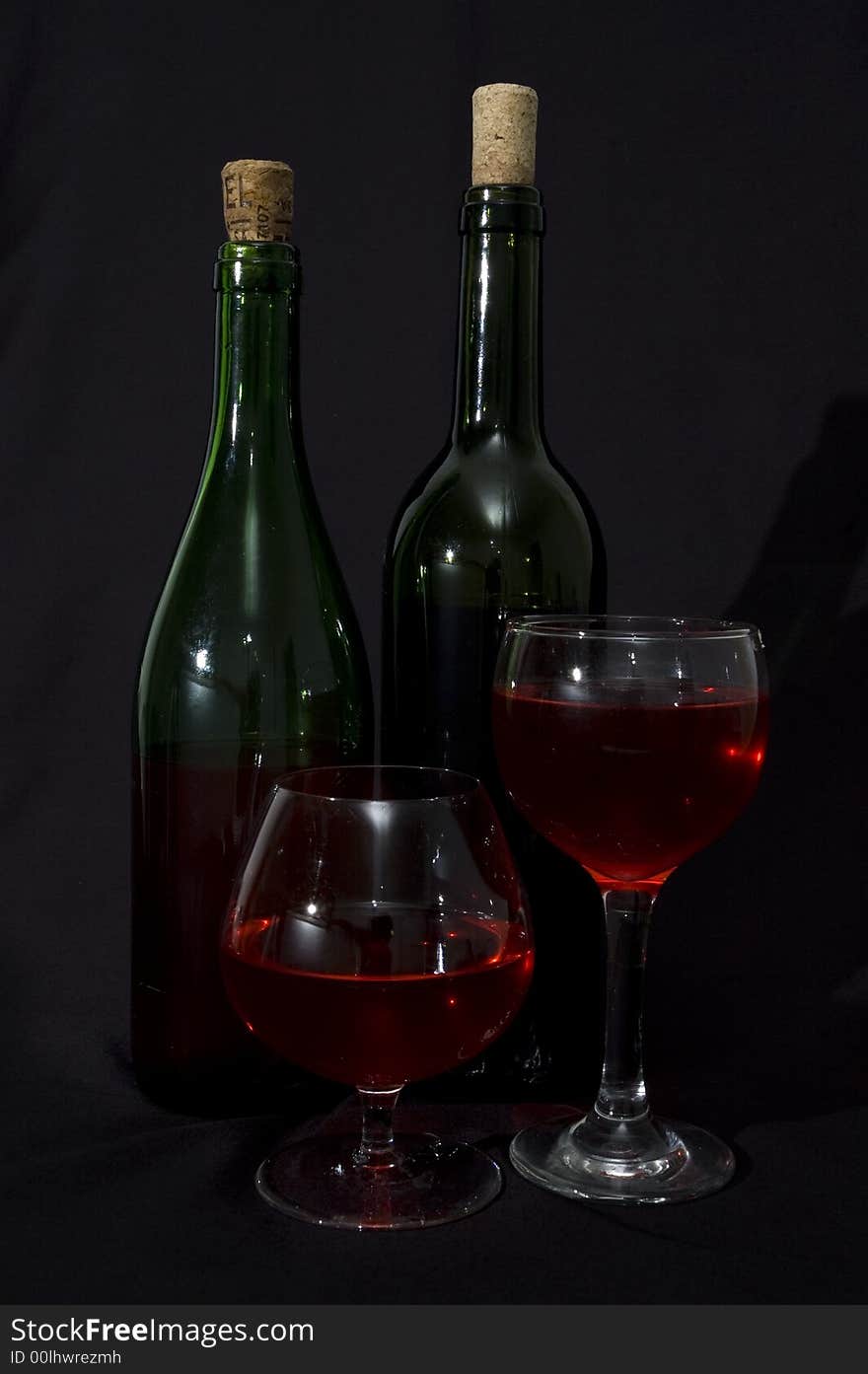 Red wine bottles and glasses isolated over black. Red wine bottles and glasses isolated over black