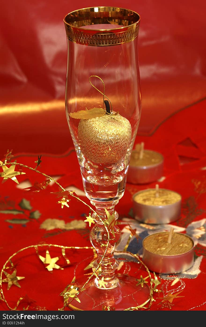 Red CHristmas table-cloth with golden apple in CHampagne glass. Red CHristmas table-cloth with golden apple in CHampagne glass