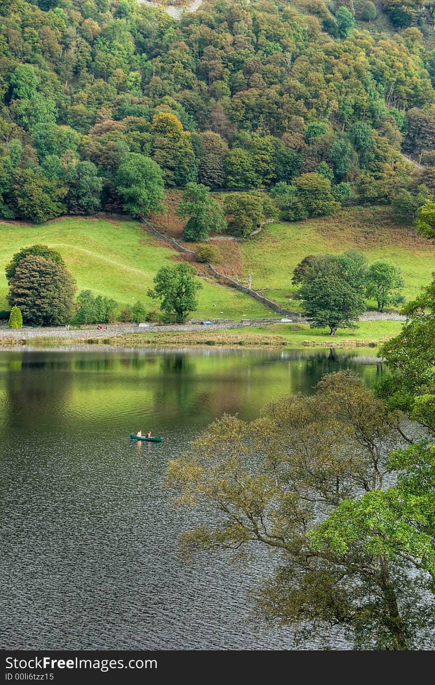 Two people canoeing on Rydal Water in the English Lake District under an overcast sky