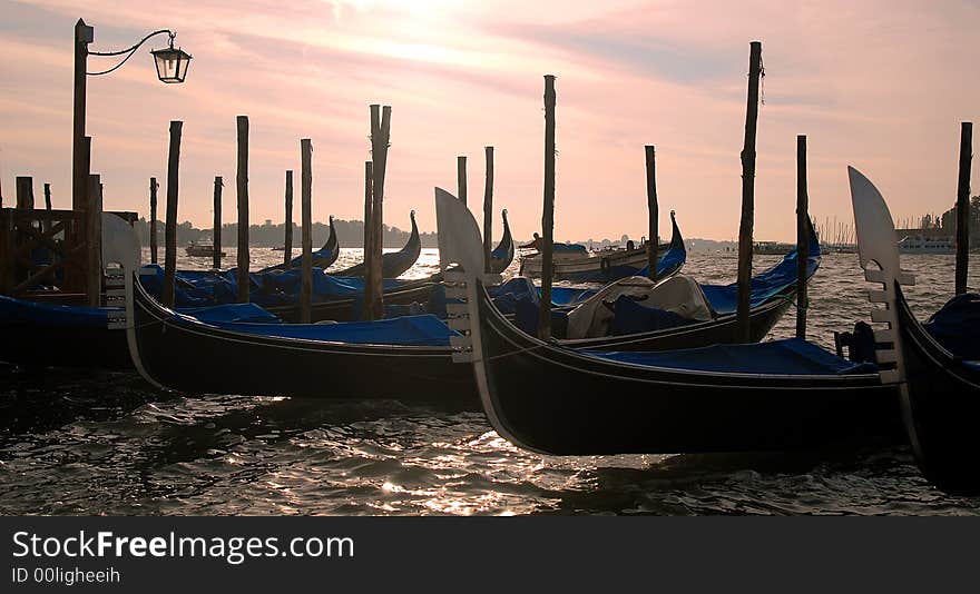 Gondola's slightly silhouetted against the bright morning sky, on the water front of the San Marco Canal and Palazzo Ducal. Gondola's slightly silhouetted against the bright morning sky, on the water front of the San Marco Canal and Palazzo Ducal.