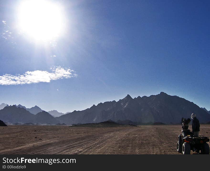 People are riding on the motorbike through the desert. People are riding on the motorbike through the desert