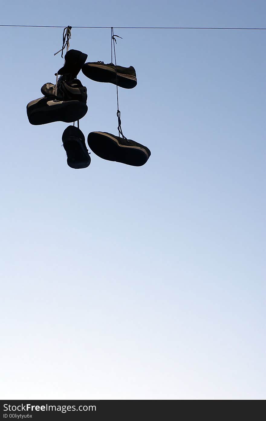 Dirty sport shoes hanging on a electric cable by the laces. Dirty sport shoes hanging on a electric cable by the laces.