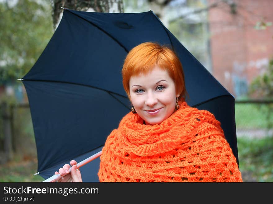 Young red-haired woman in red scarf with umbrella. Young red-haired woman in red scarf with umbrella