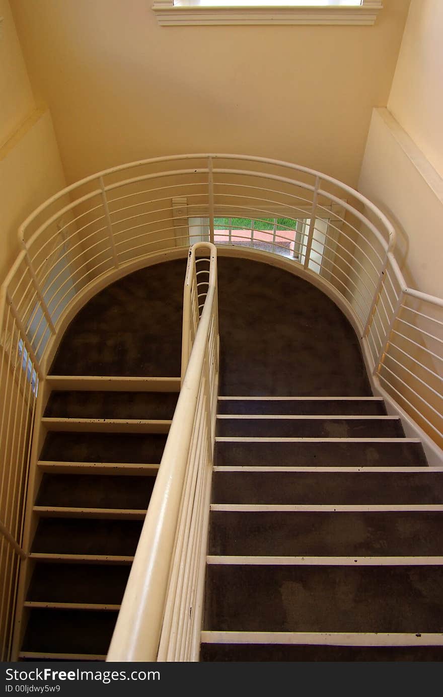 Descending metal banister and stairway inside of building. Descending metal banister and stairway inside of building