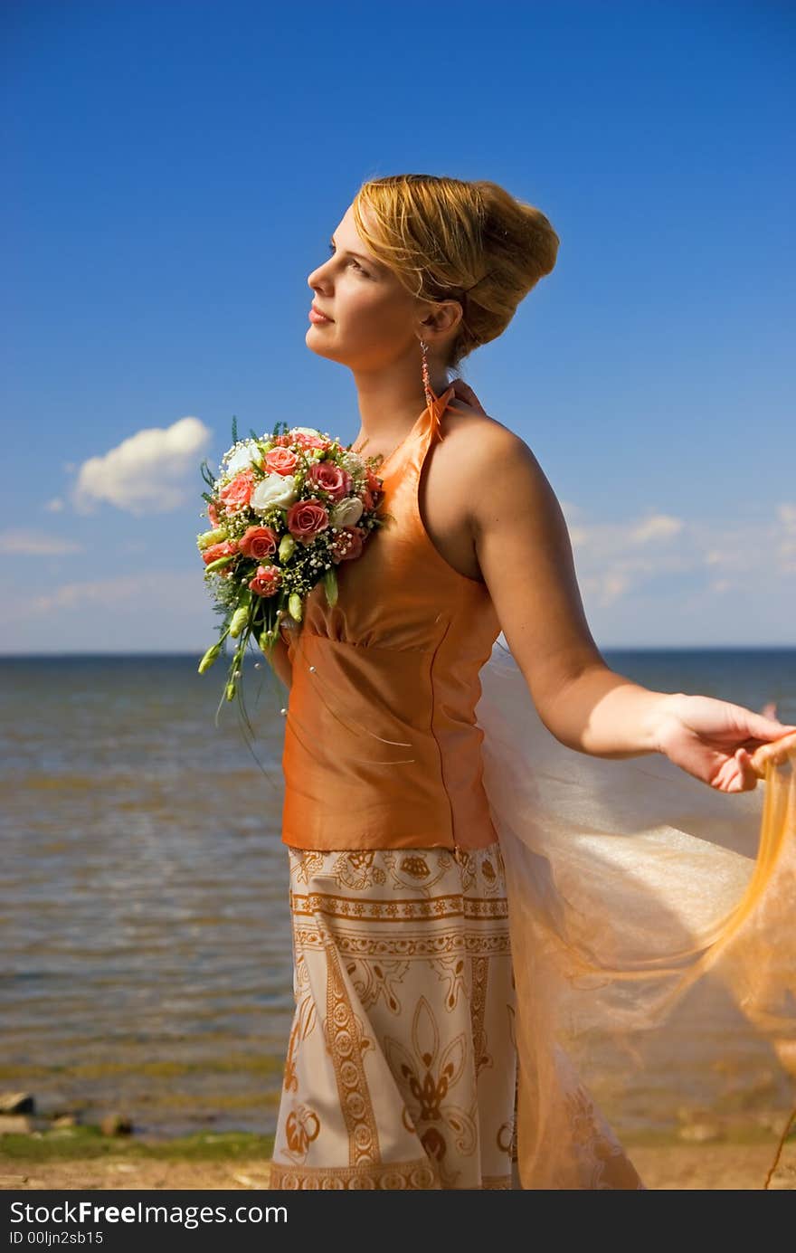 Lovely redhead lady with a bouquet of flowers near the sea