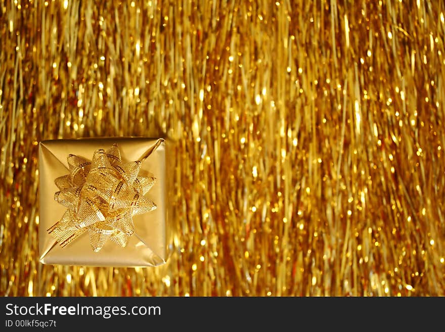 A Christmas box - a golden cube with golden ribbon, golden strings in the background. A Christmas box - a golden cube with golden ribbon, golden strings in the background.