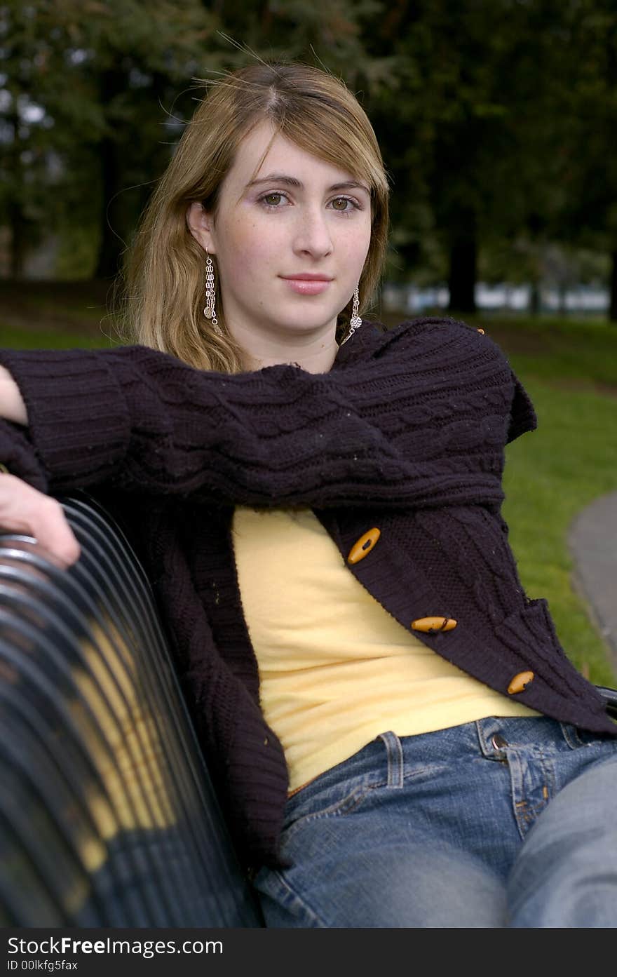 Young beautiful teen outdoors at the park with a different view, pose, scarf, and black sweater. Has a fall or winter season look.