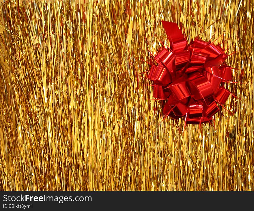 A red Christmas decoration - a ribbon shaped as a flower on golden glittering lametta strings. A red Christmas decoration - a ribbon shaped as a flower on golden glittering lametta strings.