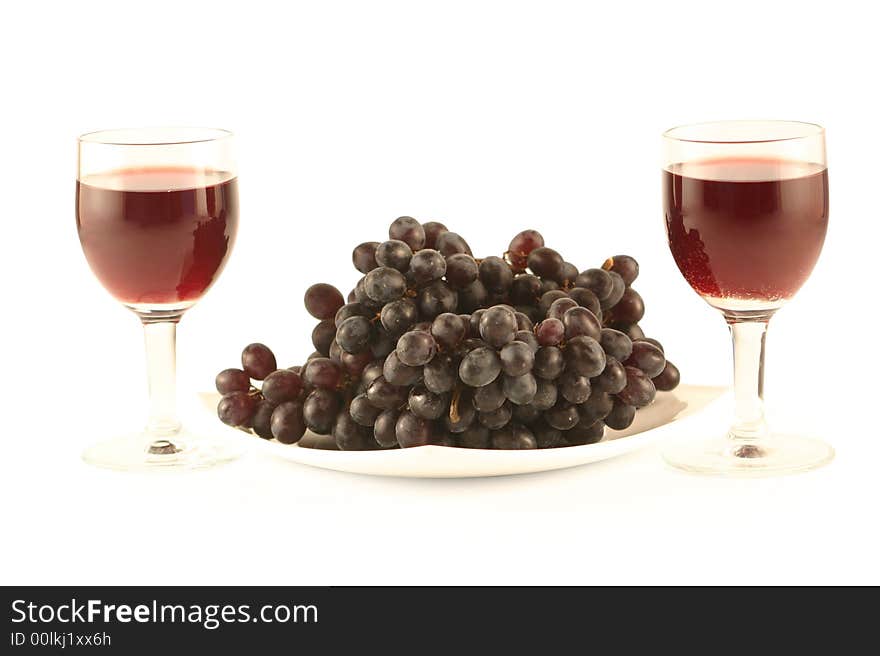 Two glasses of red wine and grapes isolated on white .