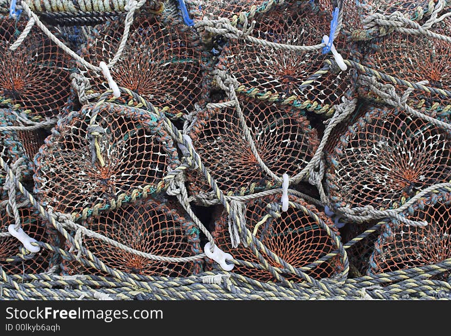 Old and well-used lobster pots stacked neatly on the quayside at a fishing port.