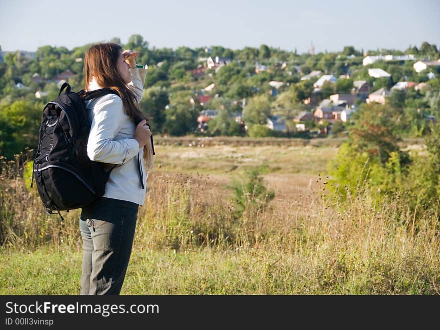 The young woman with a backpack looks afar. The young woman with a backpack looks afar