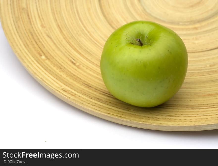 Green apple on a bamboo plate