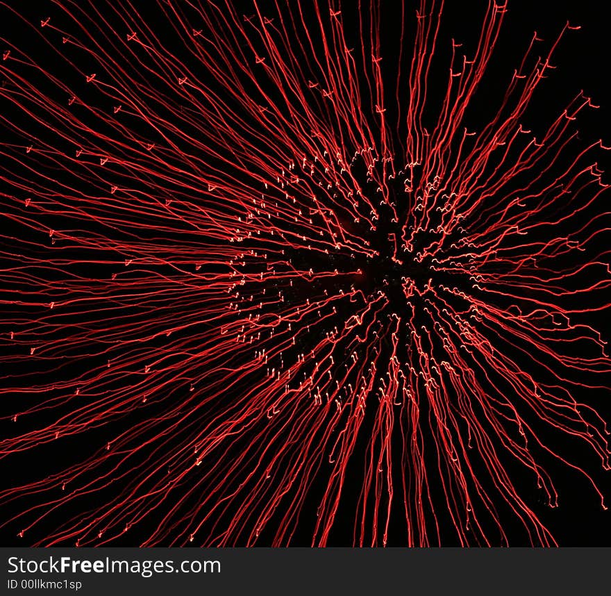 Sqiggly lines of time lapse red fireworks explosion spread across the black night sky. Sqiggly lines of time lapse red fireworks explosion spread across the black night sky