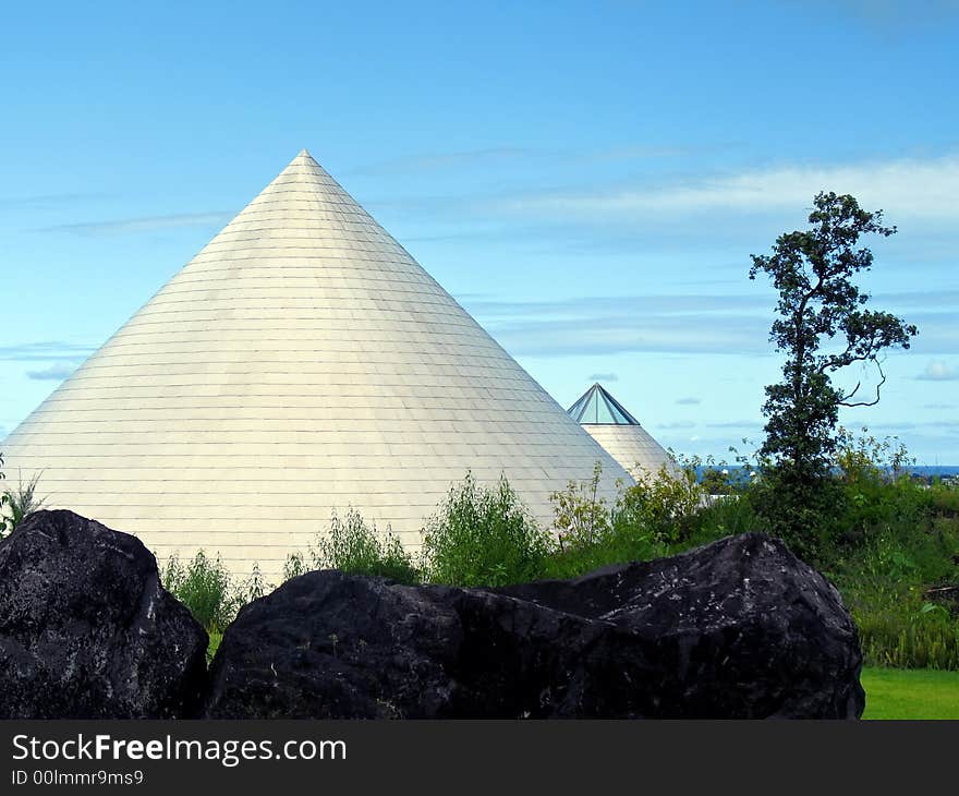 Metallic cones pointing skyward with vegetation, rocks and ocean horizon. Metallic cones pointing skyward with vegetation, rocks and ocean horizon