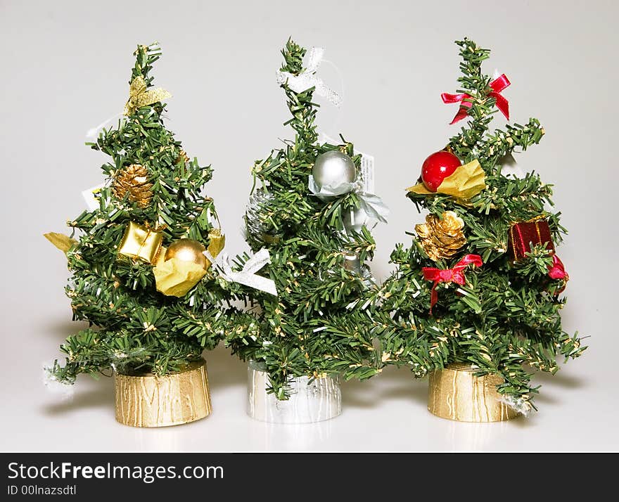 Three artificial christmas trees of green color with elegant ornaments